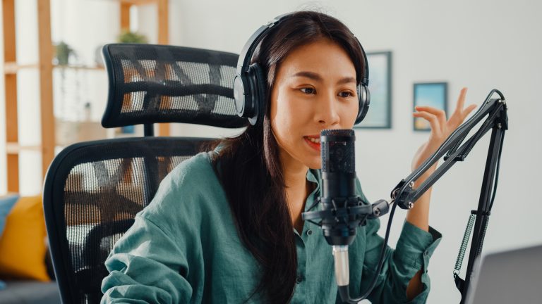 Happy asia girl record a podcast on her laptop computer with hea