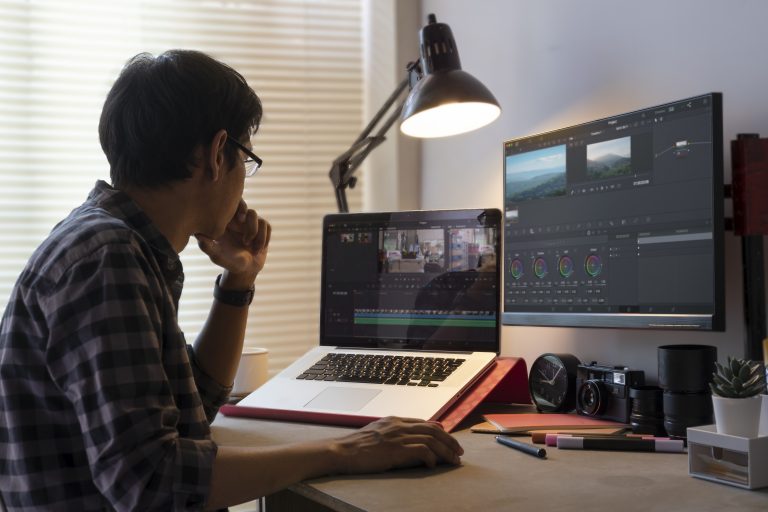 Male freelancer editing video on computer with professional prog